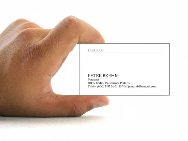 Hand hält eine Word-Visitenkartenvorlage mit Name, Position und Kontaktdaten