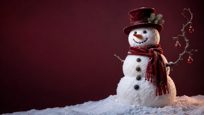 Schneemann mit rotem Schal und Zylinder vor dunkelrotem Hintergrund